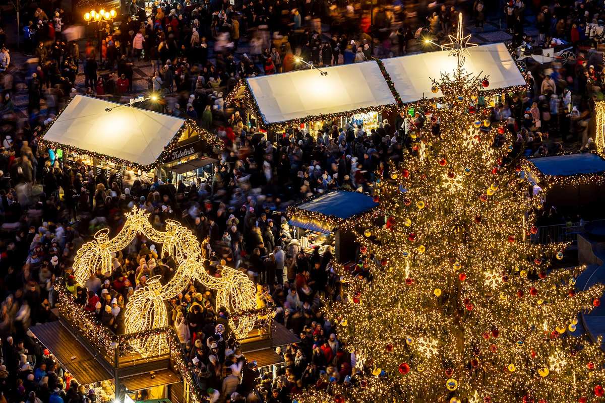 Marktstände und der Weihnachtsbaum auf dem Altstädter Ring von oben, Besucher zwischen den Hütten.