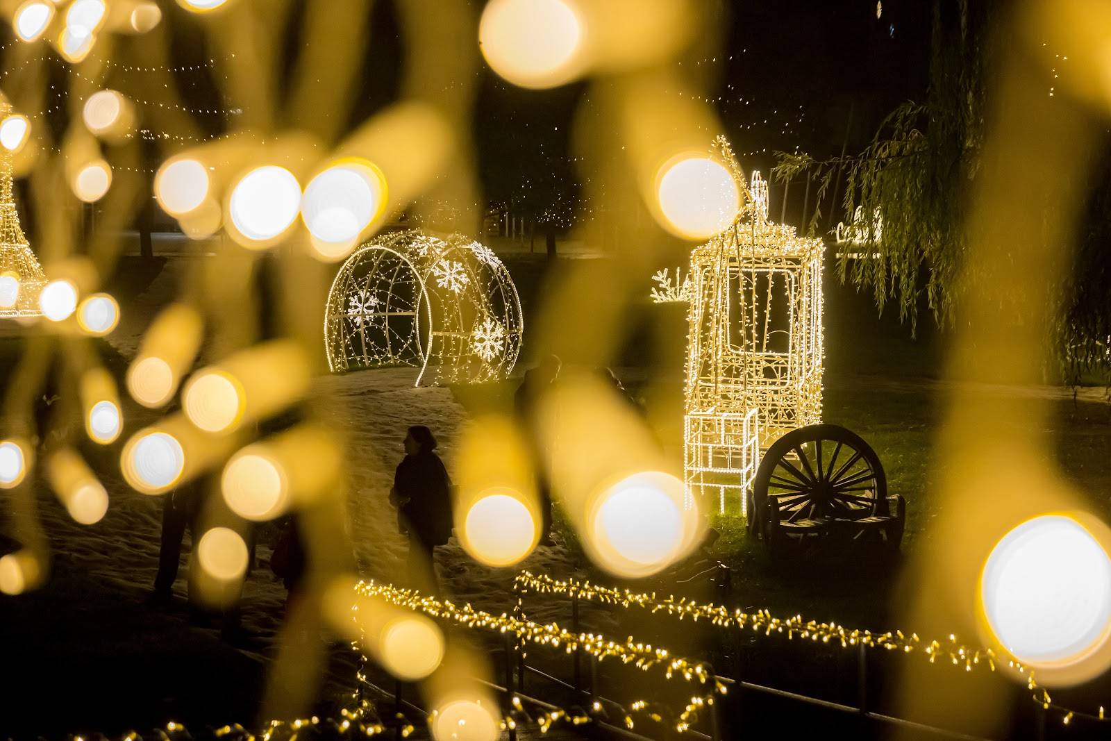 Lichtskulpturen leuchten hinter Lichterketten auf dem Weg in Žluté lázně in Prag.