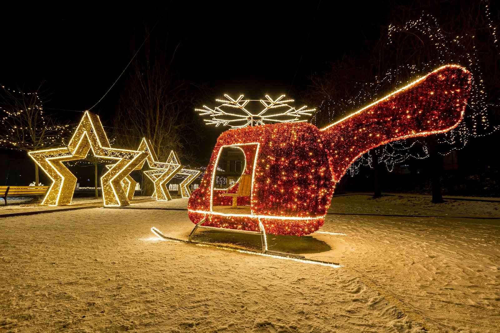 Large red light helicopter on snowy ground next to a row of glowing stars